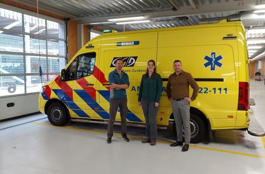 Drie mensen poseren voor een ambulance