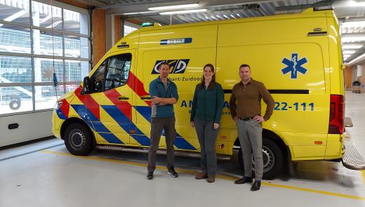 Drie mensen poseren voor een ambulance